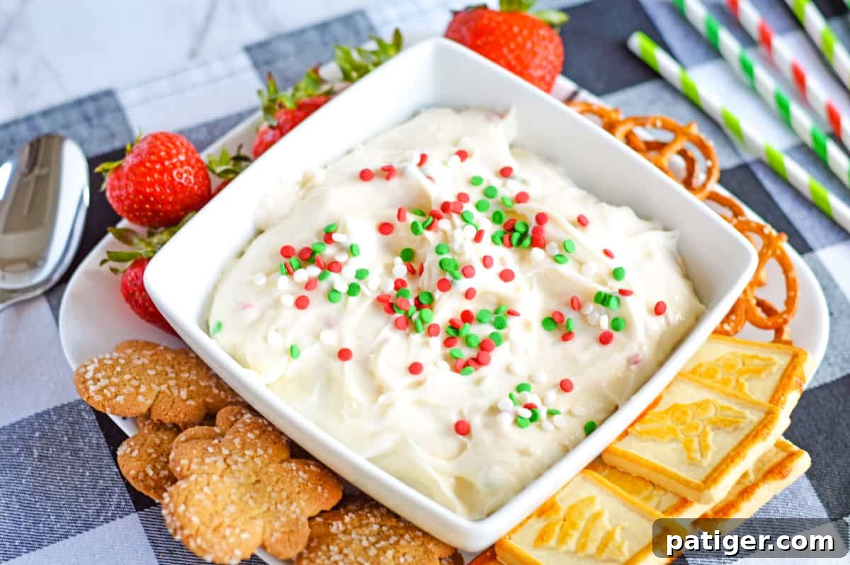 A festive spread featuring Christmas dessert dip, beautifully arranged with an assortment of Christmas cookies, vibrant red strawberries, and crunchy pretzels, inviting guests to dip and enjoy.