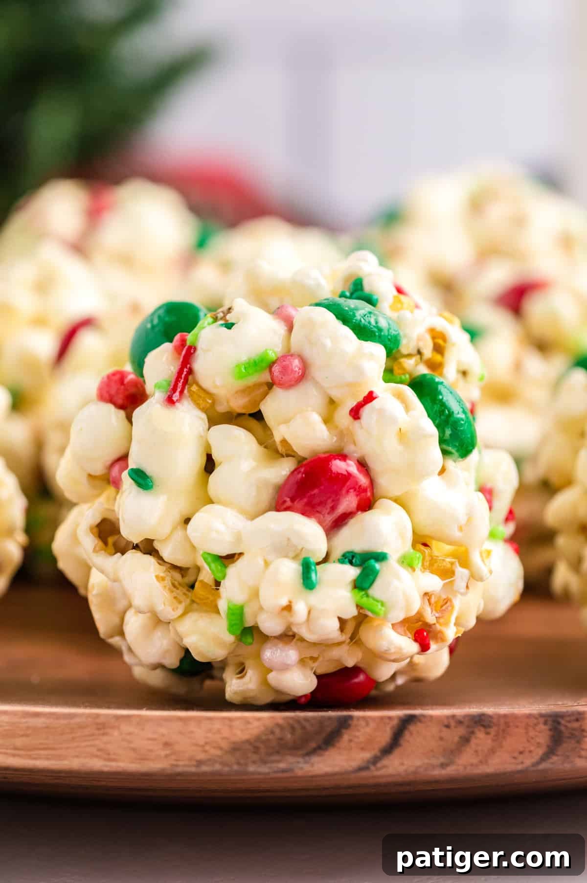 A close-up shot of a single Christmas popcorn ball, showcasing its festive sprinkles and colorful M&Ms.