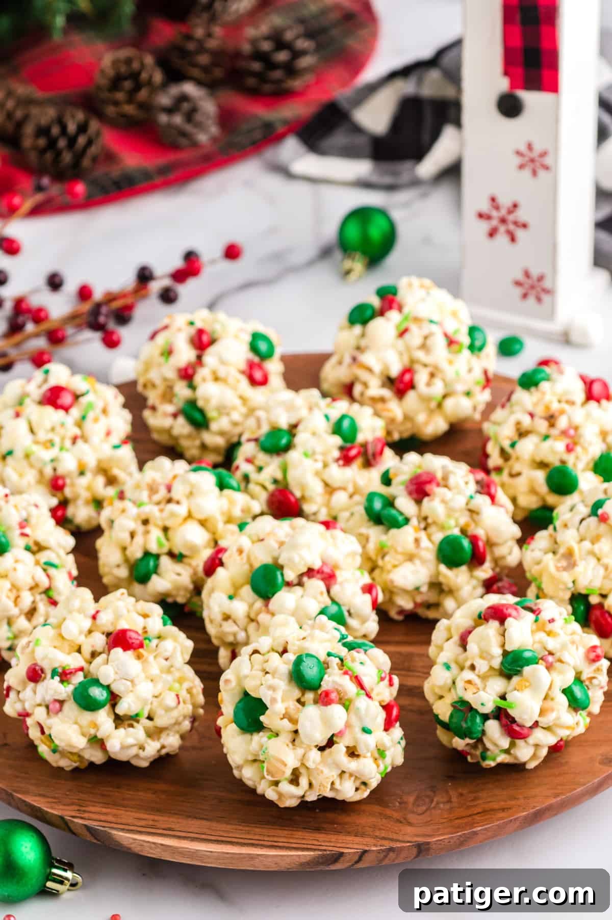 Christmas popcorn balls with marshmallows, red and green M&Ms, and sprinkles, beautifully arranged on a wooden serving platter, ready to be enjoyed.
