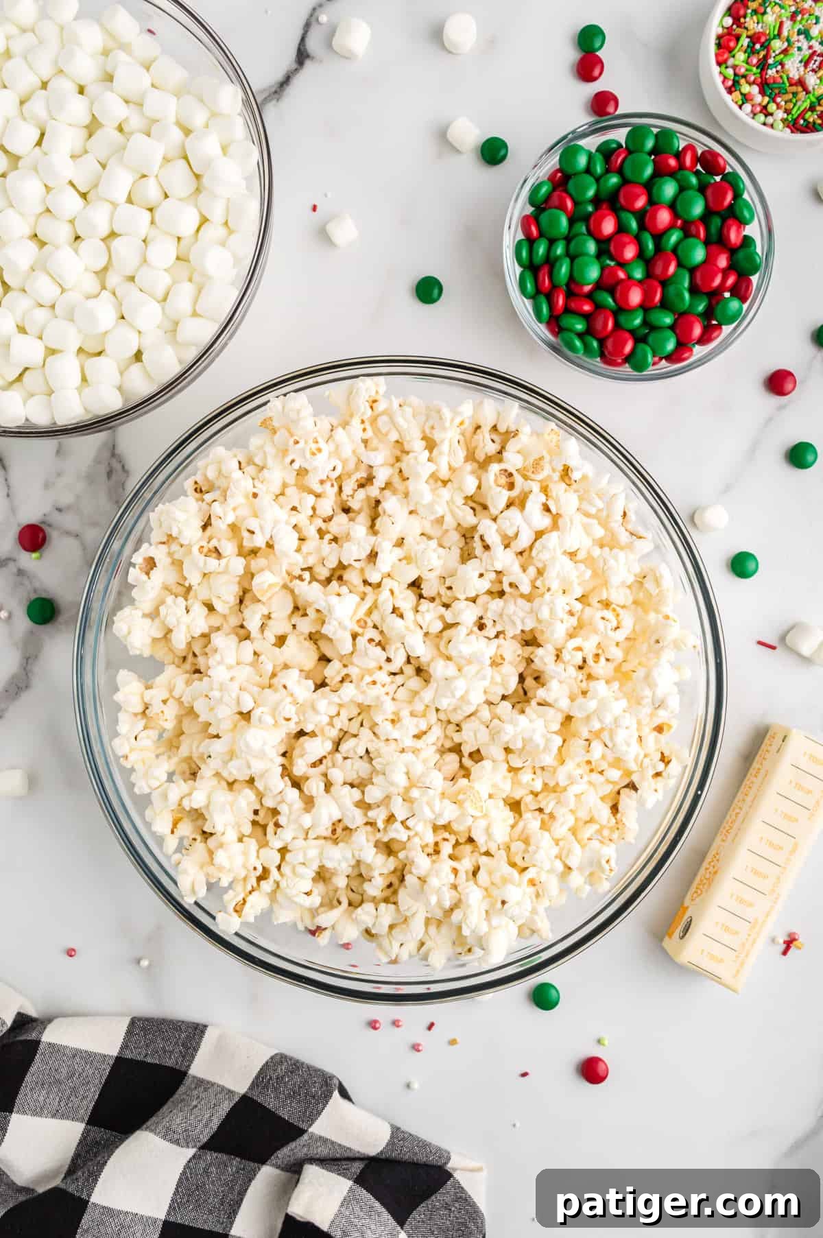 A large glass bowl filled with freshly popped popcorn, ready for the next step of making popcorn balls.