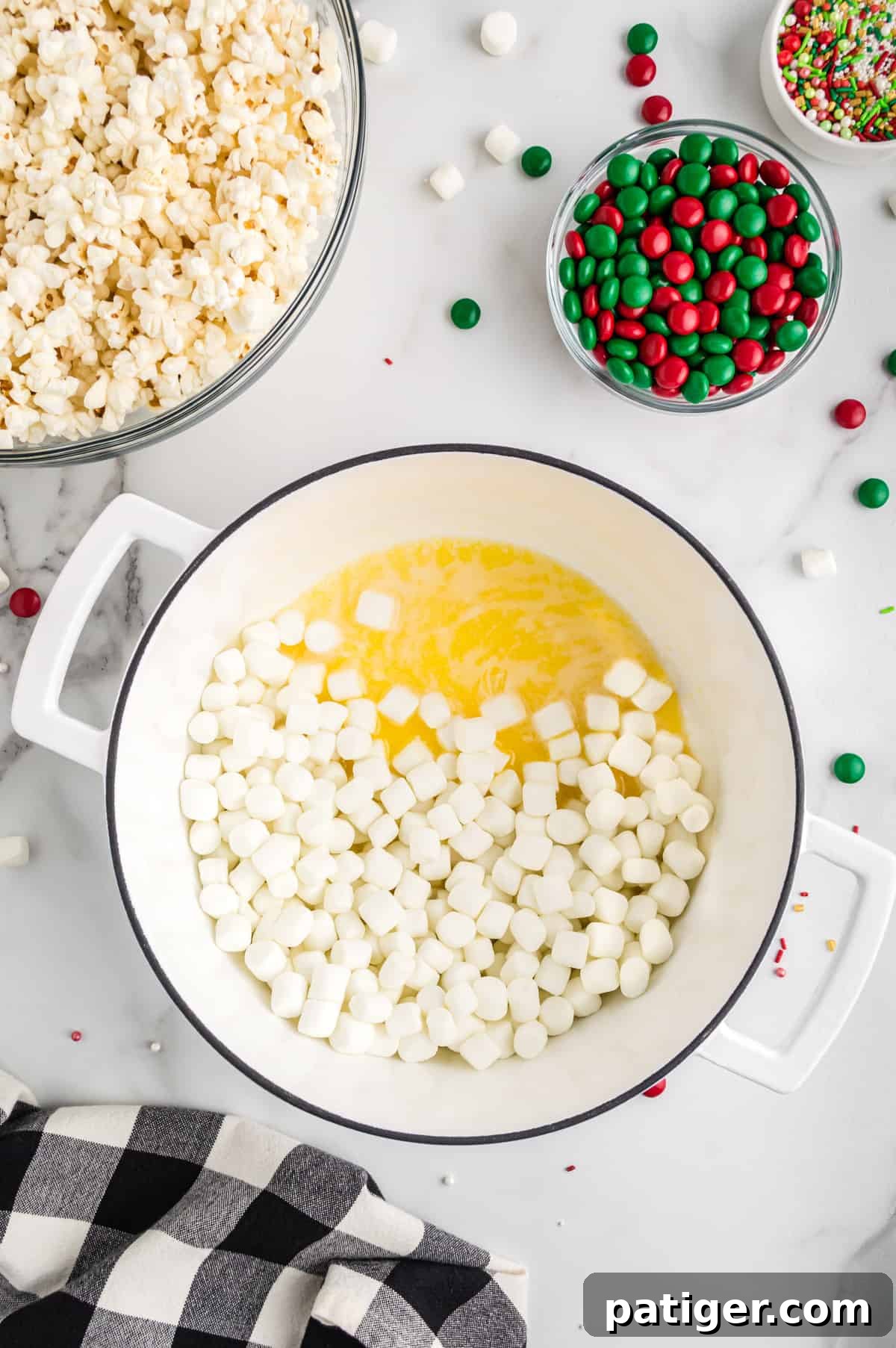 Melted butter combined with miniature marshmallows in a large pot, forming a smooth, gooey mixture.