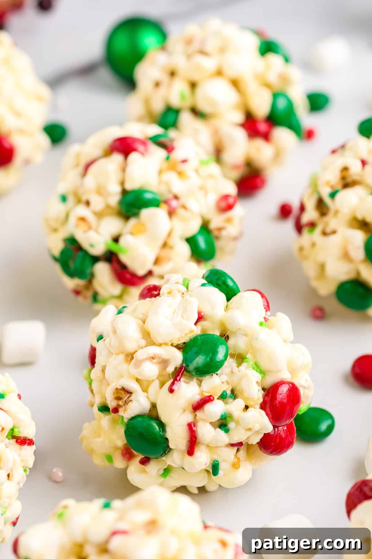 Freshly formed popcorn balls, studded with M&Ms and sprinkles, cooling on a tray.