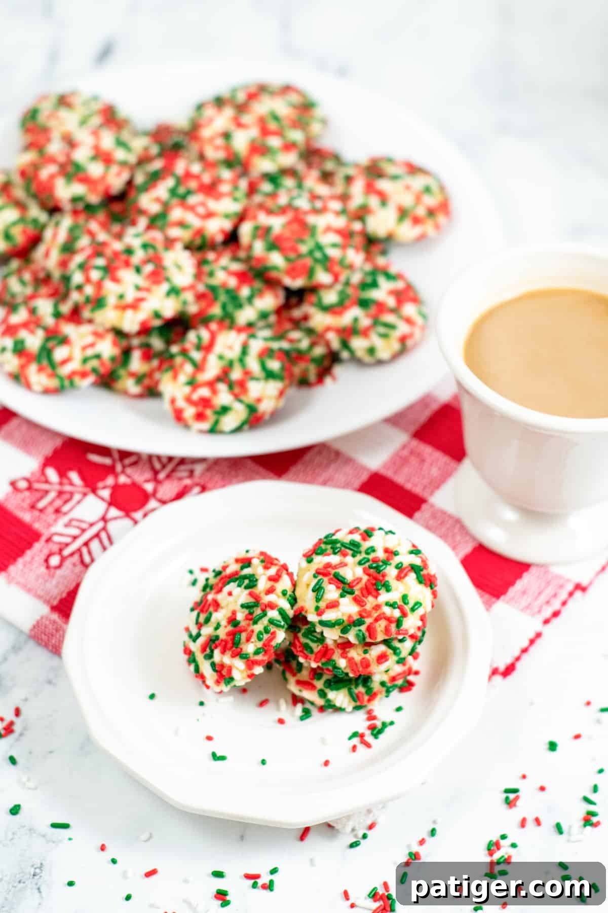 Soft christmas sprinkle cookies on large white plate and a smaller serving on small white plate with cup of coffee next to it