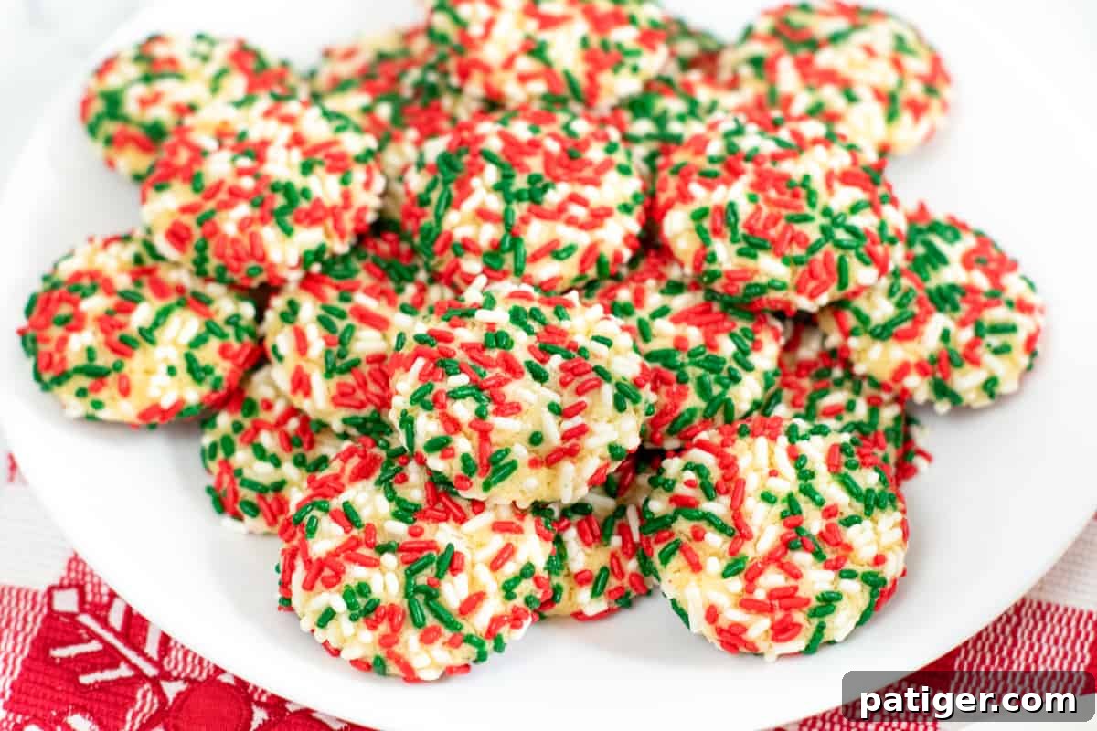 Round cookies with red, green and white sprinkles stacked on a serving plate