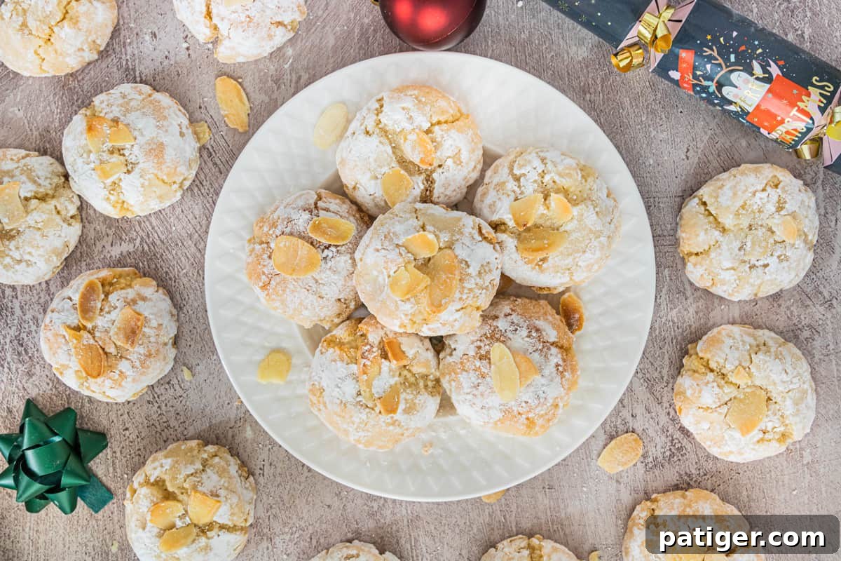 Soft Amaretti Cookies piled on a white plate surrounded by more cookies and christmas supplies