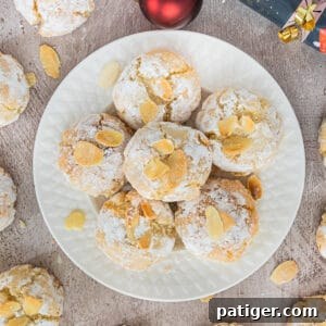 Soft Amaretti Cookies piled on a white plate surrounded by more cookies