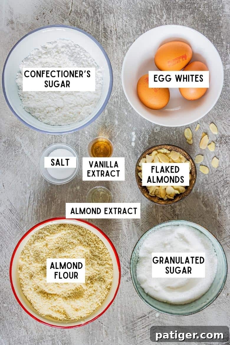 Ingredients on countertop: almond flour, granulated sugar, salt, confectioners sugar, 3 medium size eggs, vanilla extract, almond extract, flaked almonds 