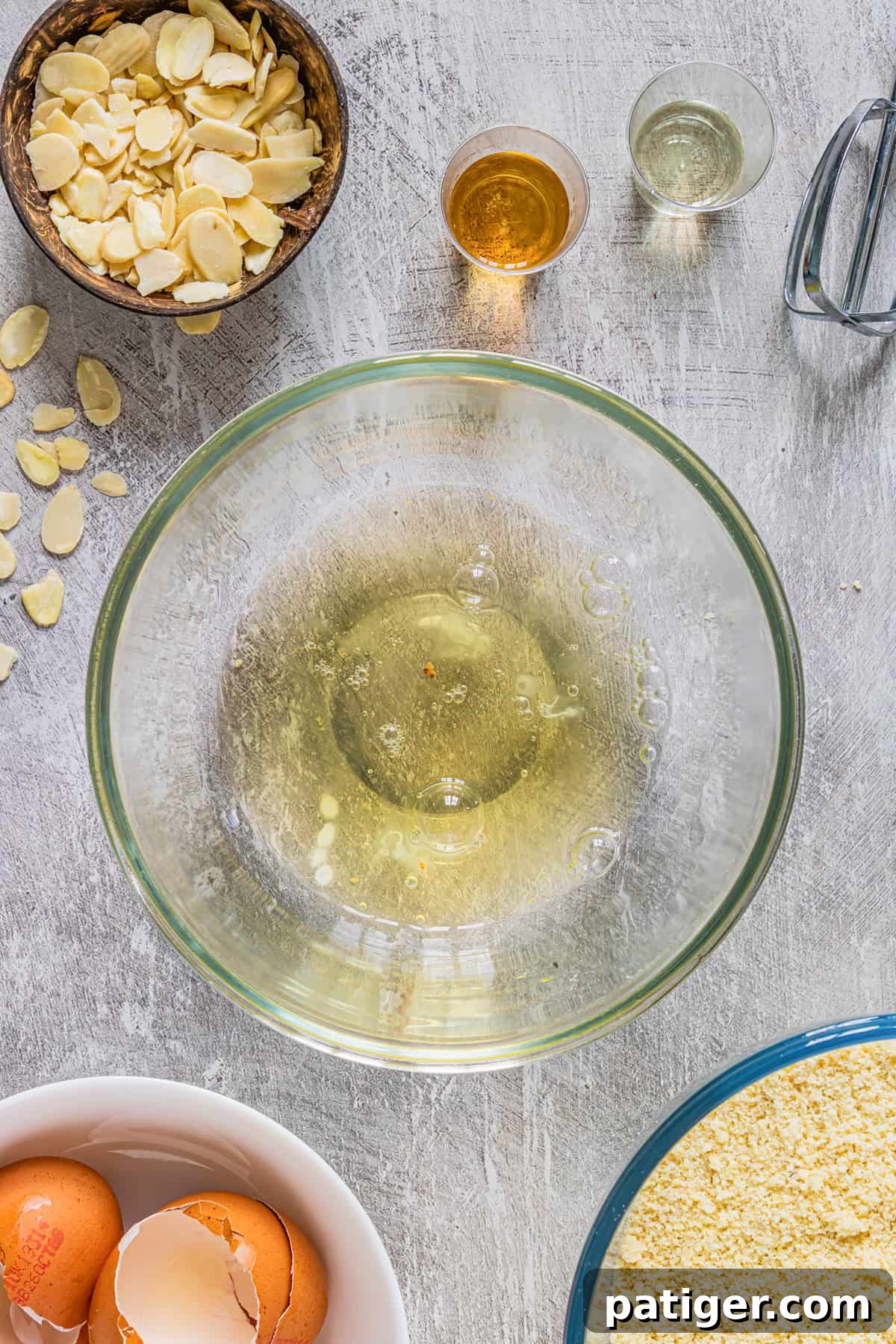 egg whites in a glass bowl with electronic mixer next to it 
