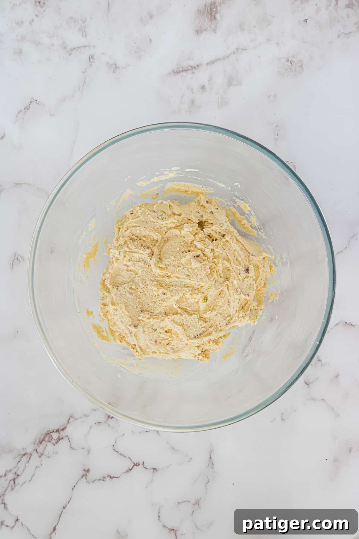 Crimson Swirl Snowball Delights 5 A close-up view of freshly mixed Peppermint Snowball Cookie dough, clearly showing the inclusion of crushed red and green candy canes and finely chopped pecans.
