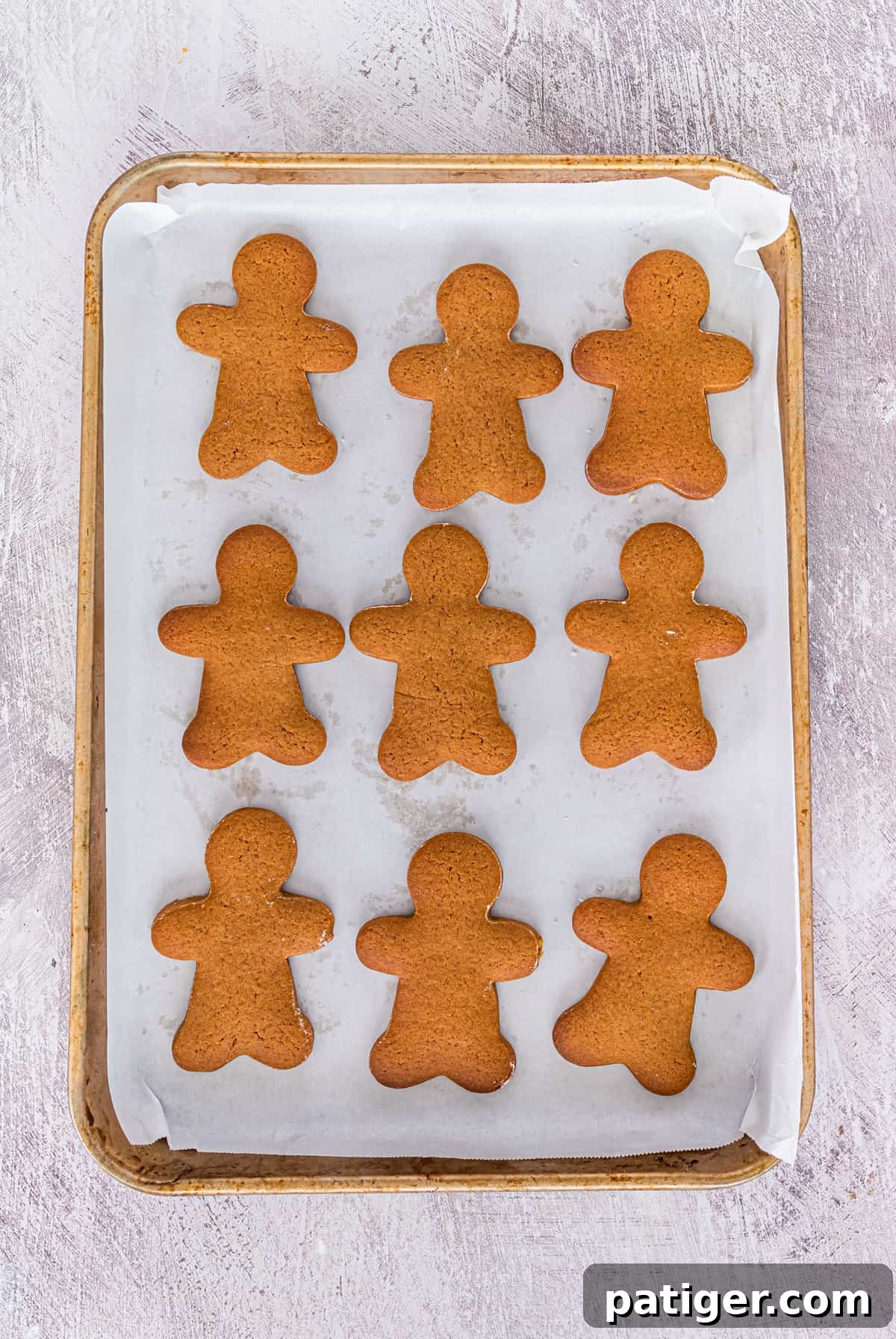 Undecorated gingerbread men cookies on parchment-lined baking sheet