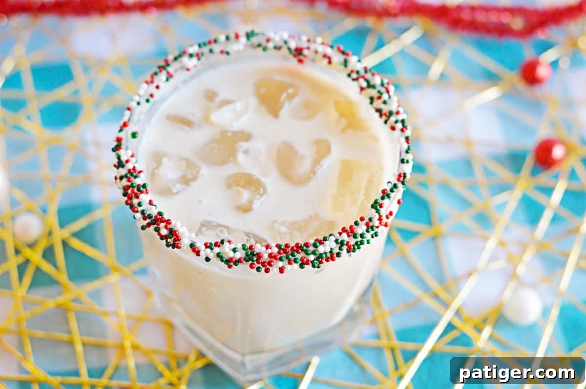 White creamy cocktail in glass with ice and cristmas sprinkles on rim