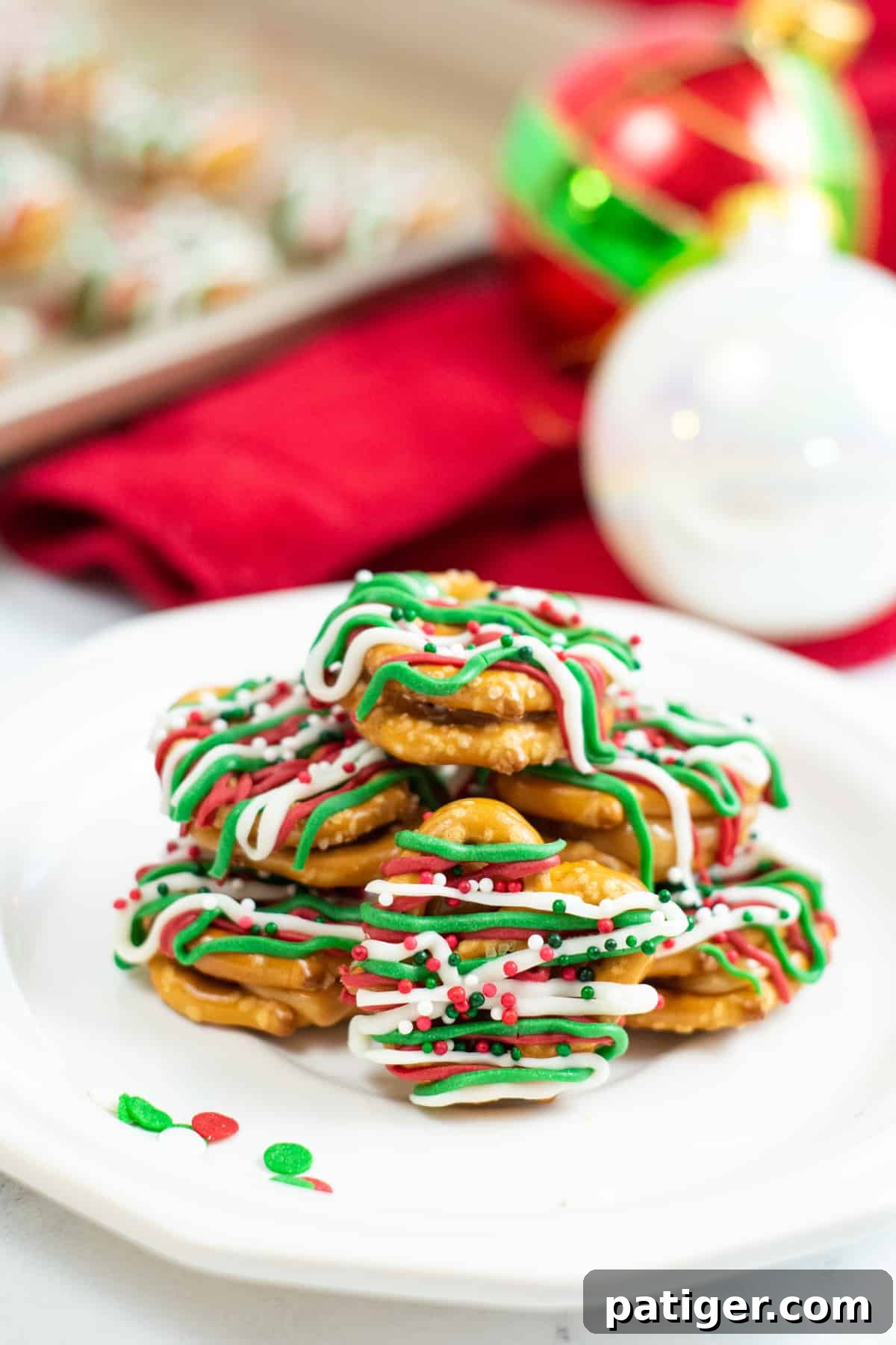 Holiday Pretzel Poppers 2 Caramel pretzel bites drizzled with green, red, and white candy melts and topped with holiday sprinkles, arranged on a festive tray.