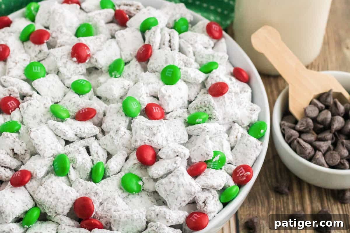 Bowl of Christmas Reindeer Chow made with Chex cereal and M&Ms, with glass of milk and chocolate chips in background