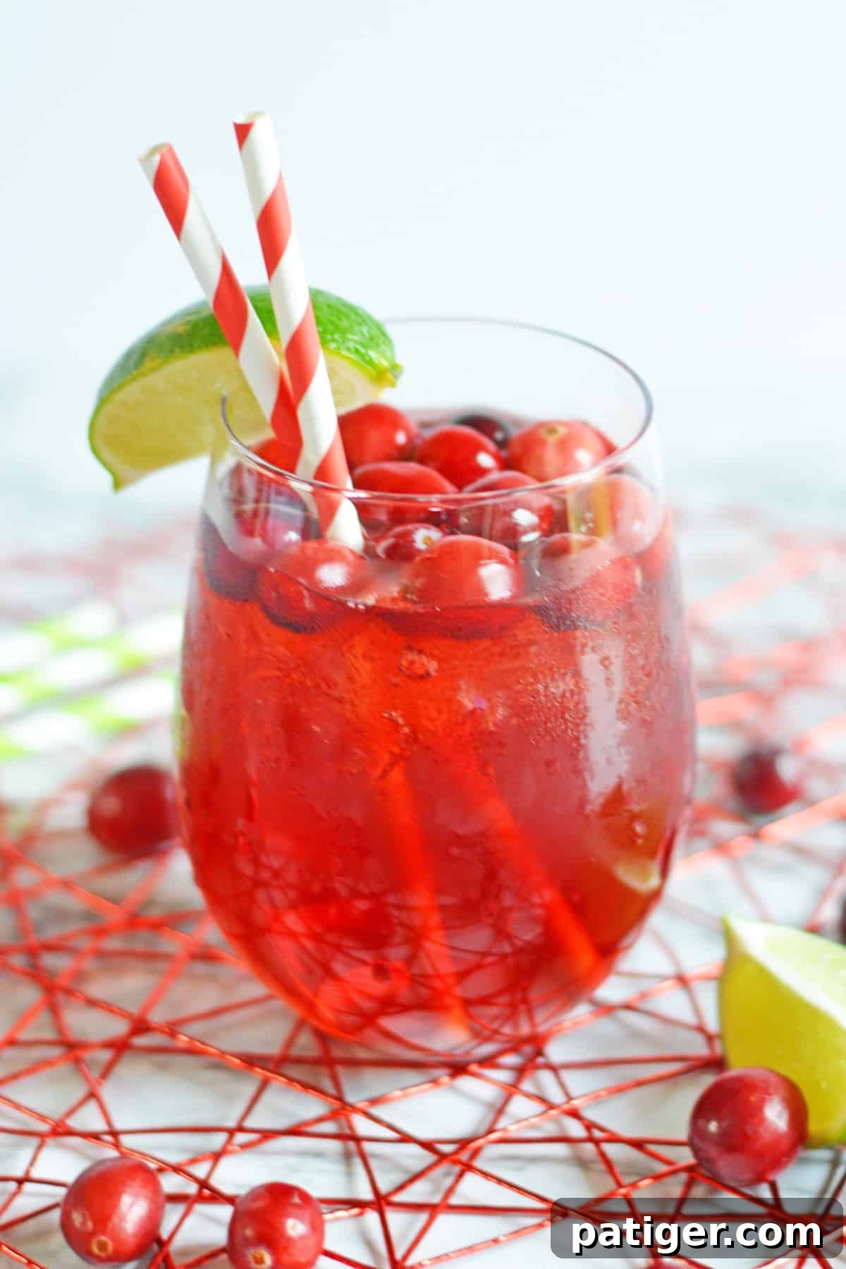 Refreshing Vodka Cranberry cocktail in a short wine glass, garnished with a vibrant lime wedge and fresh cranberries, perfect for any celebration.