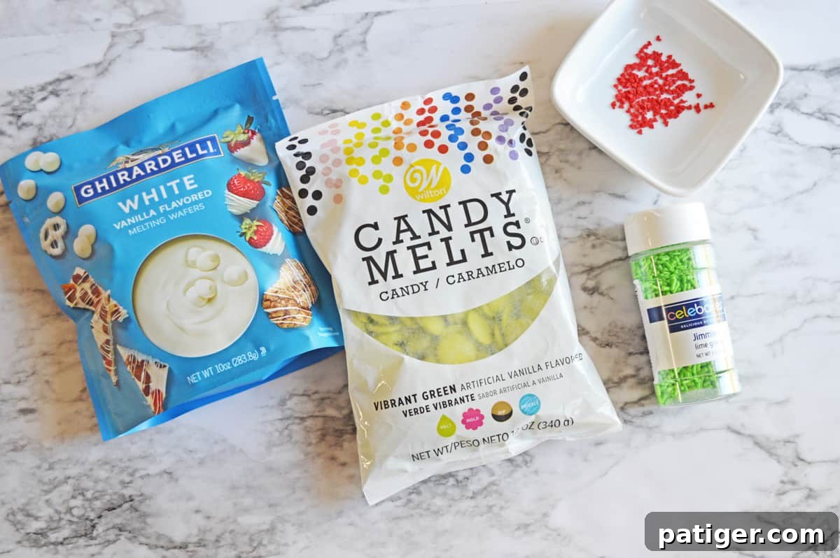 Close-up of Grinch Bark ingredients: Ghirardelli White vanilla melting wafers, Wilton vibrant green candy melts, festive green sprinkles, and adorable red heart sprinkles.