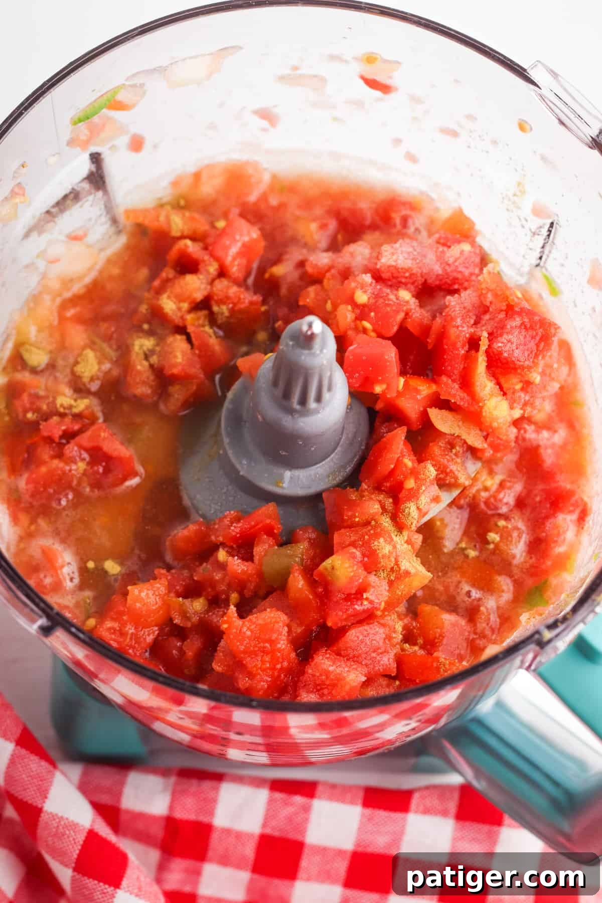 Food processor containing perfectly blended Rotel salsa ingredients, showcasing the vibrant red color and smooth consistency, ready for chilling.