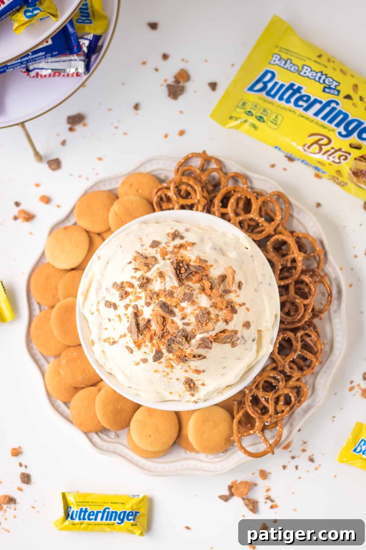 Butterfinger Fluff Dip, a no-bake dessert, beautifully presented with pretzel twists and golden vanilla wafers, ready for dipping.