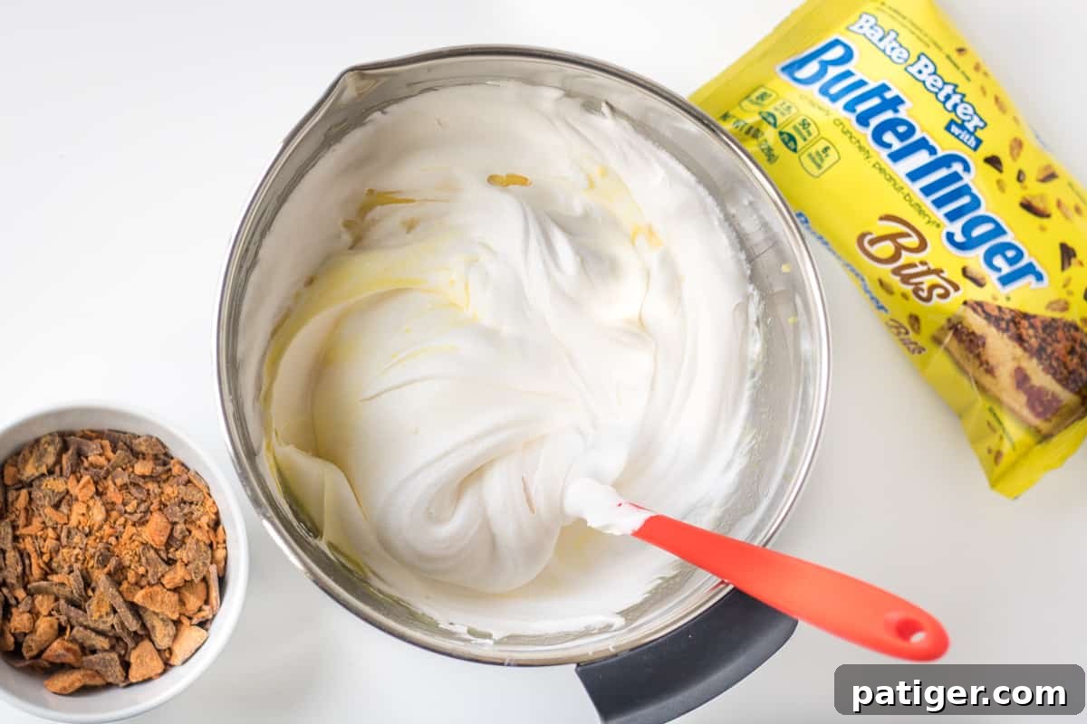 Thickened vanilla pudding gently mixed with whipped topping in a large bowl, creating a fluffy texture.