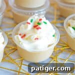 Christmas sugar cookie jello shot topped with whipped cream and red and green jimmies
