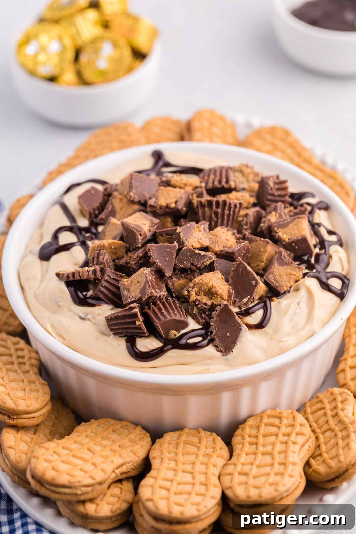 Reese's Peanut Butter Cup Dip in white serving bowl served on a platter with Nutter Butter Cookies for dipping.