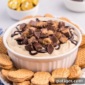 Reese's Peanut Butter Cup Dip in white serving bowl served on a platter with Nutter Butter Cookies for dipping.
