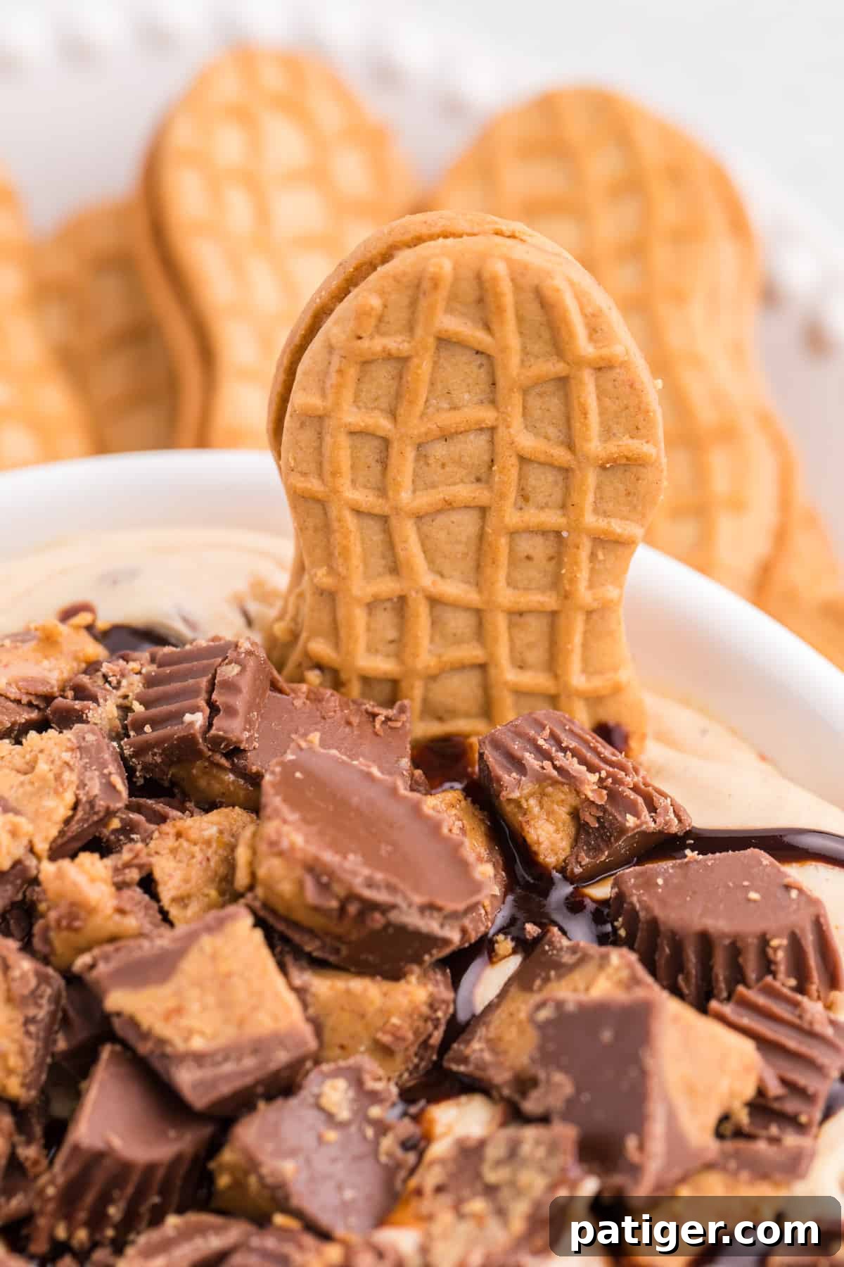 Nutter Butter Cookie sticking out of Reese's Peanut Butter Cup Dip with more cookies in the background.