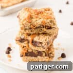 Carmelitas Cookies with sticky caramel oozing out sliced into squares and stacked on top of each other on a white plate