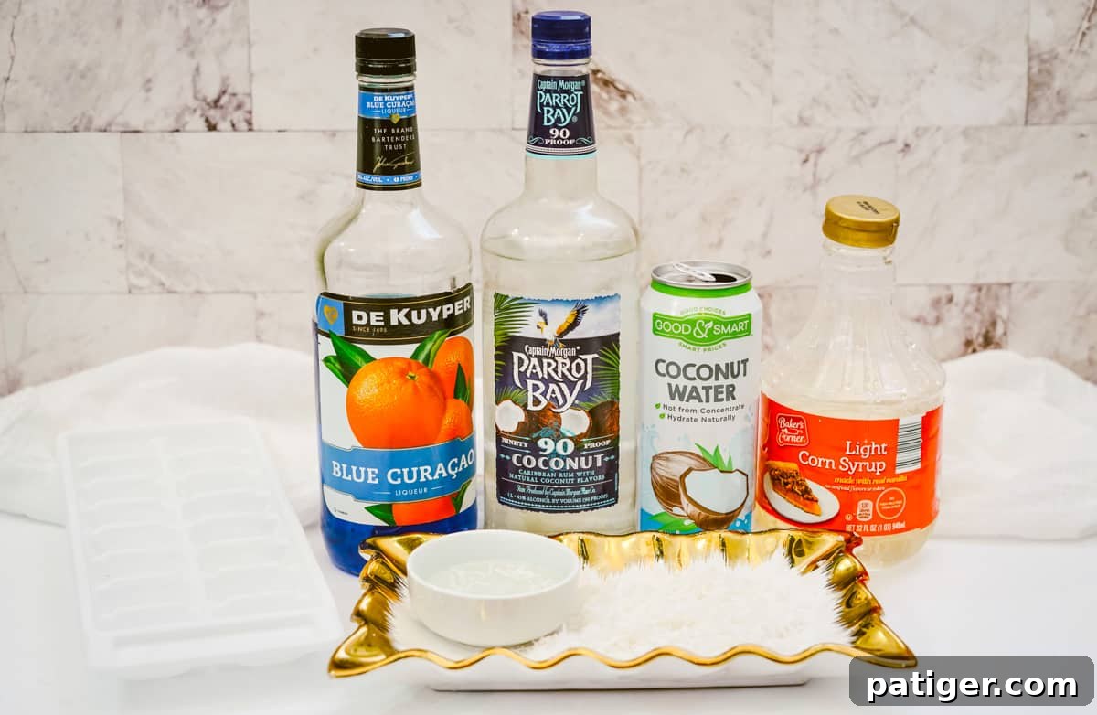 Tray displaying ice cubes, a bottle of blue Curaçao, a bottle of Captain Morgan Parrot Bay coconut rum, a can of coconut water, a bottle of light corn syrup, and a shallow platter with coconut flakes.