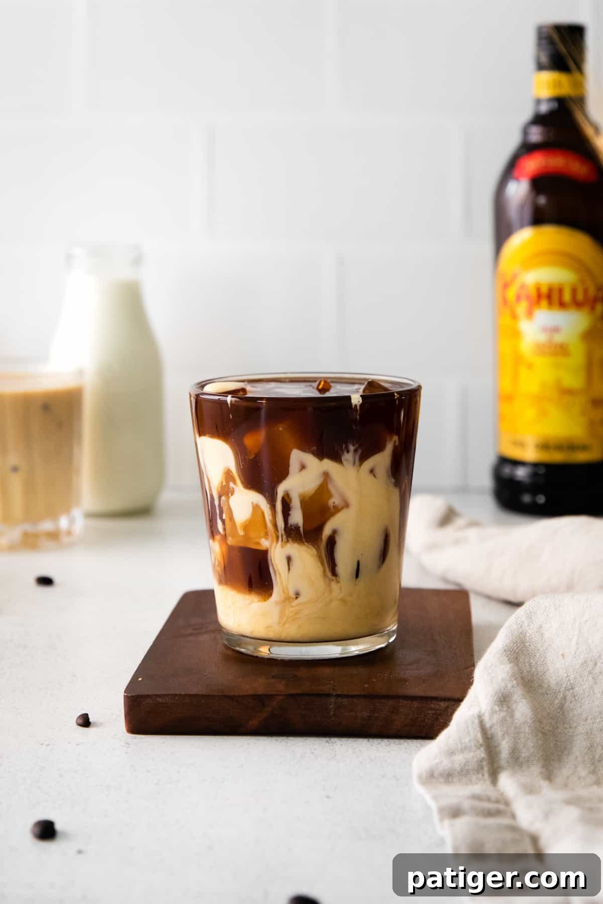 Festive Eggnog White Russian 3 An unstirred Eggnog White Russian cocktail showing distinct layers of coffee liqueur and creamy eggnog, ready to be mixed for a beautiful holiday drink.