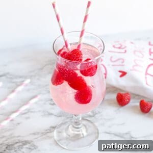Pink Moscato Sangria with fresh raspberries in a cocktail glass with pink and white striped paper straws