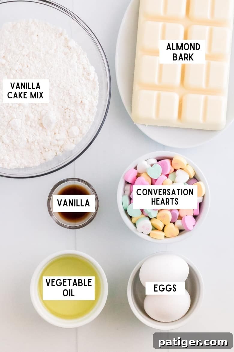 Bowl of vanilla cake mix, blocks of almond bark, bowl of conversation heart candies, bowl of vanilla extract, 2 large eggs, bowl of vegetable oil