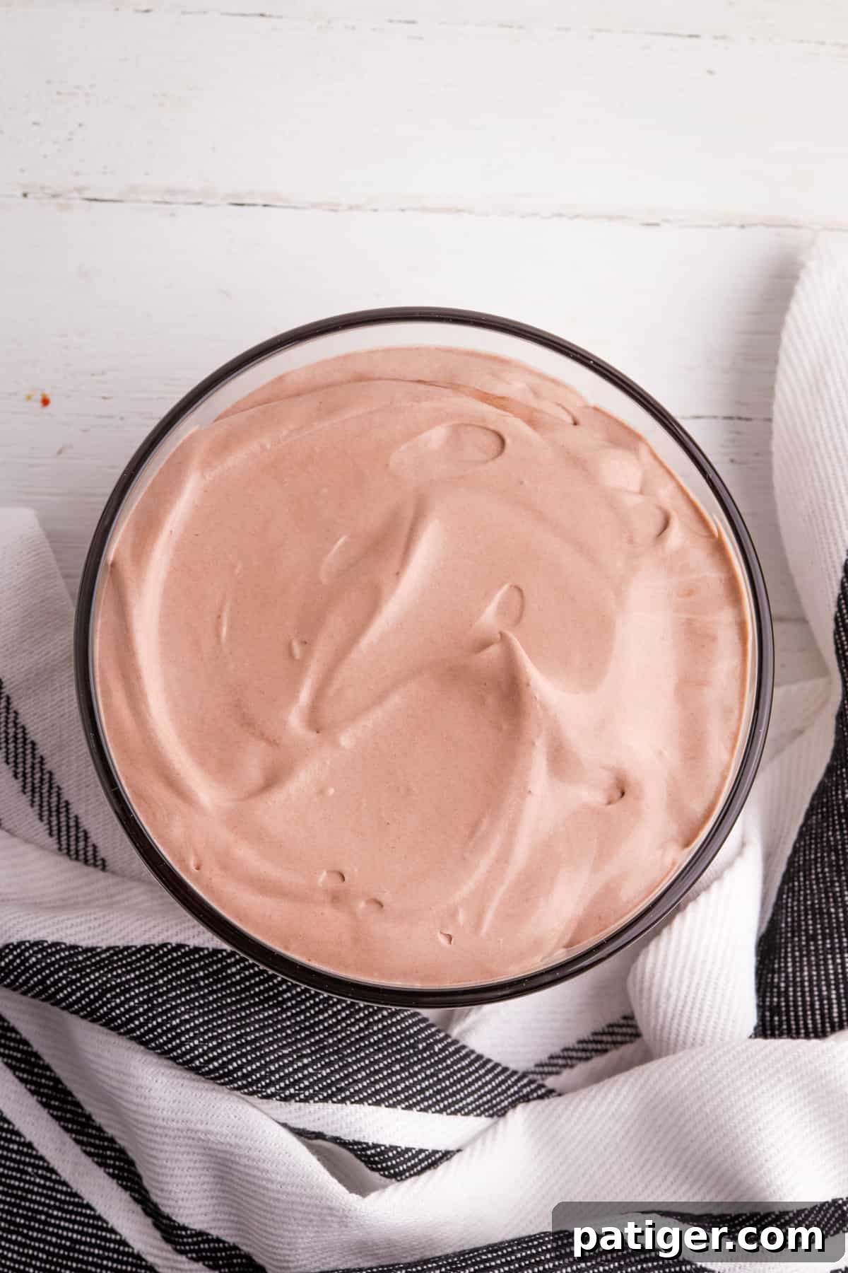 Two-layered chocolate pudding and whipped topping dip in a serving bowl, ready for chilling and garnishing.