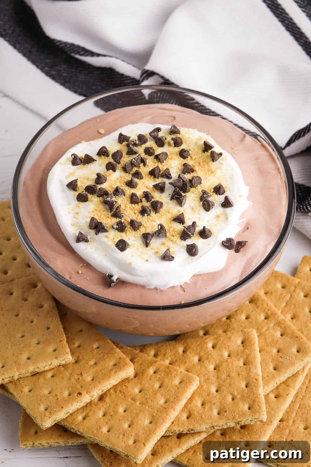 Chocolate pudding and whipped topping dip garnished with mini chocolate chips and graham cracker crumbs, surrounded by dippers.
