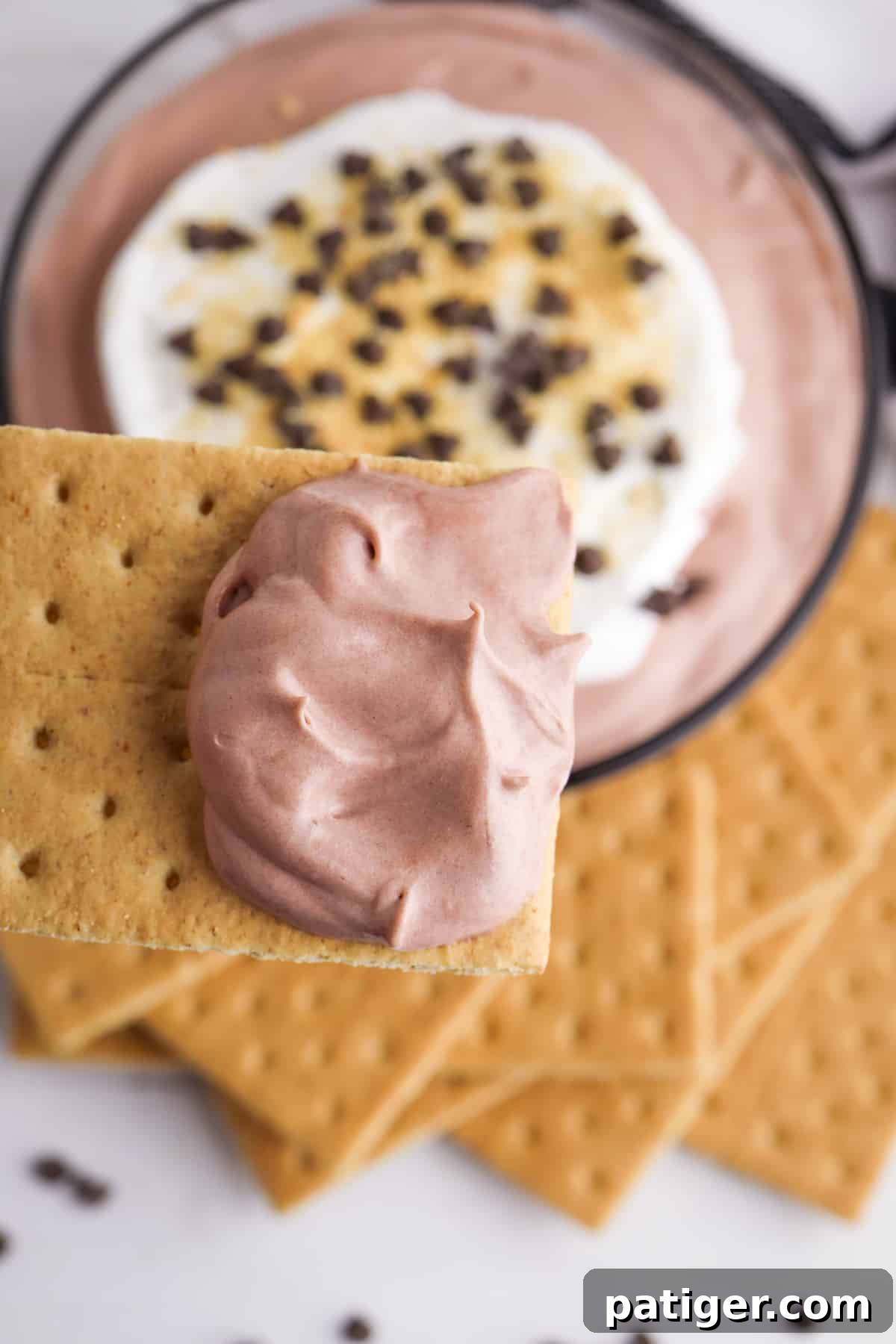 A graham cracker generously scooped with creamy chocolate pudding dip, highlighting the perfect texture.