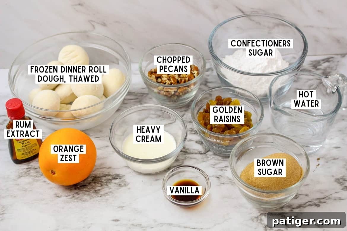 Bottle of imitation rum extract, one orange, and the following ingredients in bowls: rhodes frozen dinner rolls, chopped pecans, confectioners sugar, golden raisins, brown sugar, vanilla, heavy cream, vanilla, and hot water