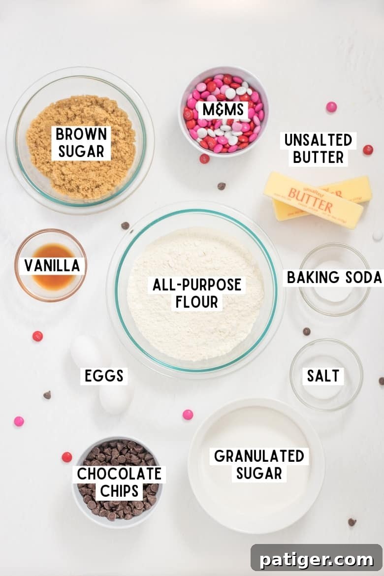 Two eggs, 2 sticks of butter, and bowls of: red, pink, and white M&Ms; light brown sugar; granulated sugar; salt; baking soda; chocolate chips; vanilla; and all-purpose flour