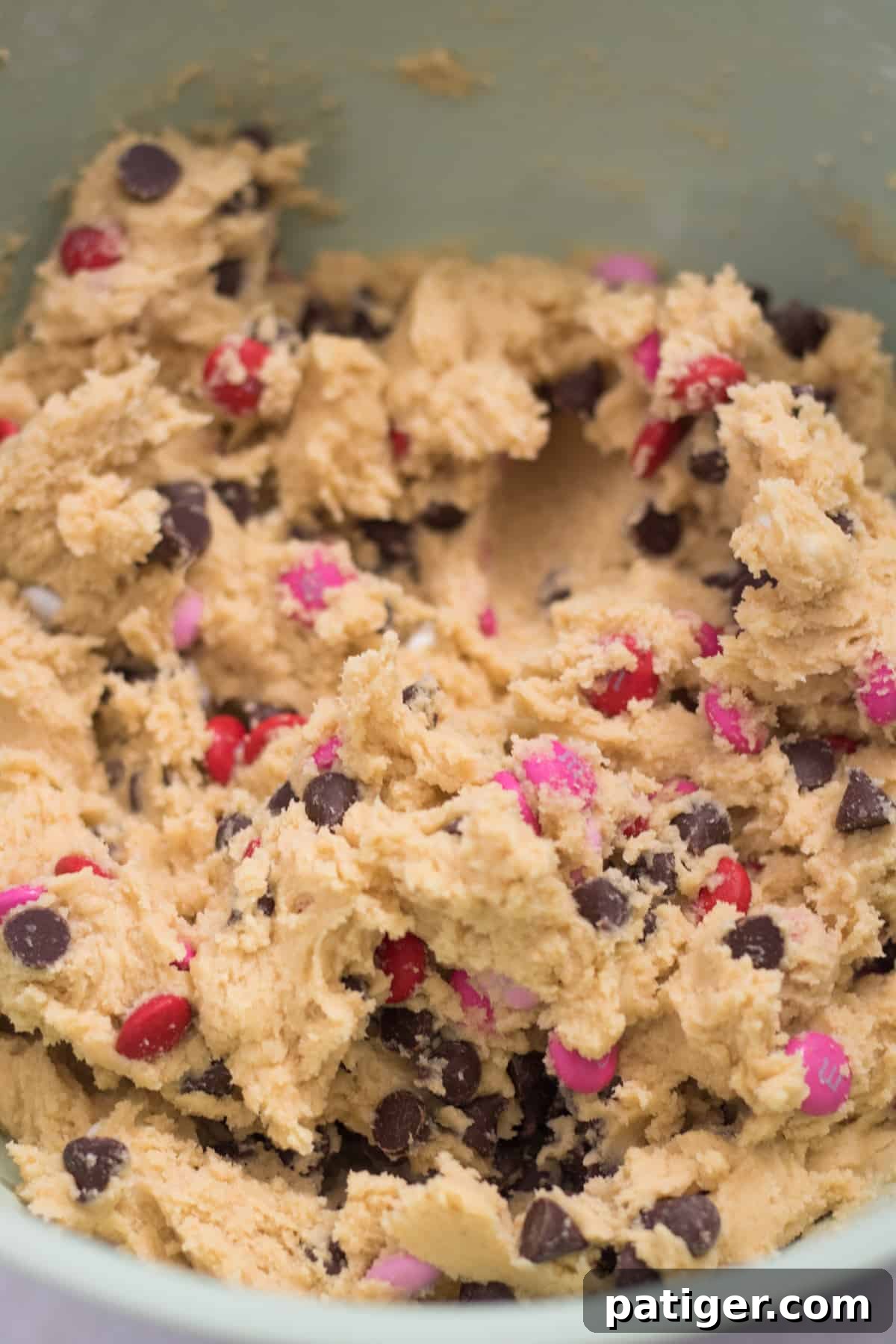Chocolate chip cookie dough with pink, red, and white M&Ms