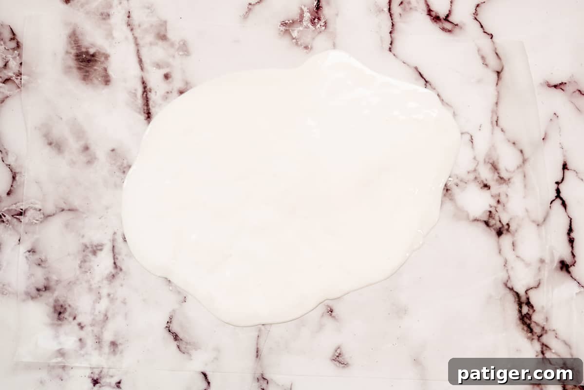 Melted white candy spread thinly and evenly on wax paper, forming the base for an Easter bark, ready for decoration.