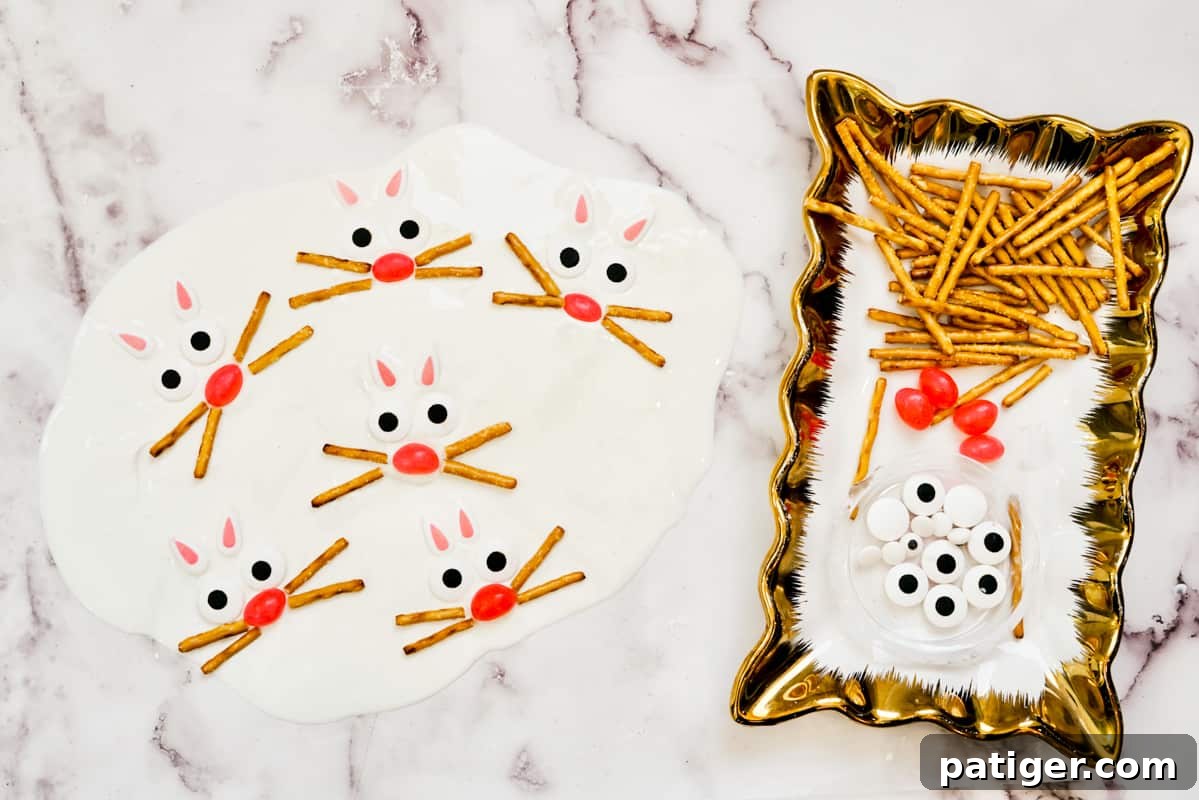 A collection of pretzels, pink jelly beans, and candy eyes ready for decorating, arranged next to a partially decorated white candy bark with bunny faces taking shape, illustrating the creative process.