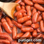 Sweet Glazed Slow Cooker Smokies 11 Little Smokies Cocktail Sausages in a slow cooker with a wooden spoon.