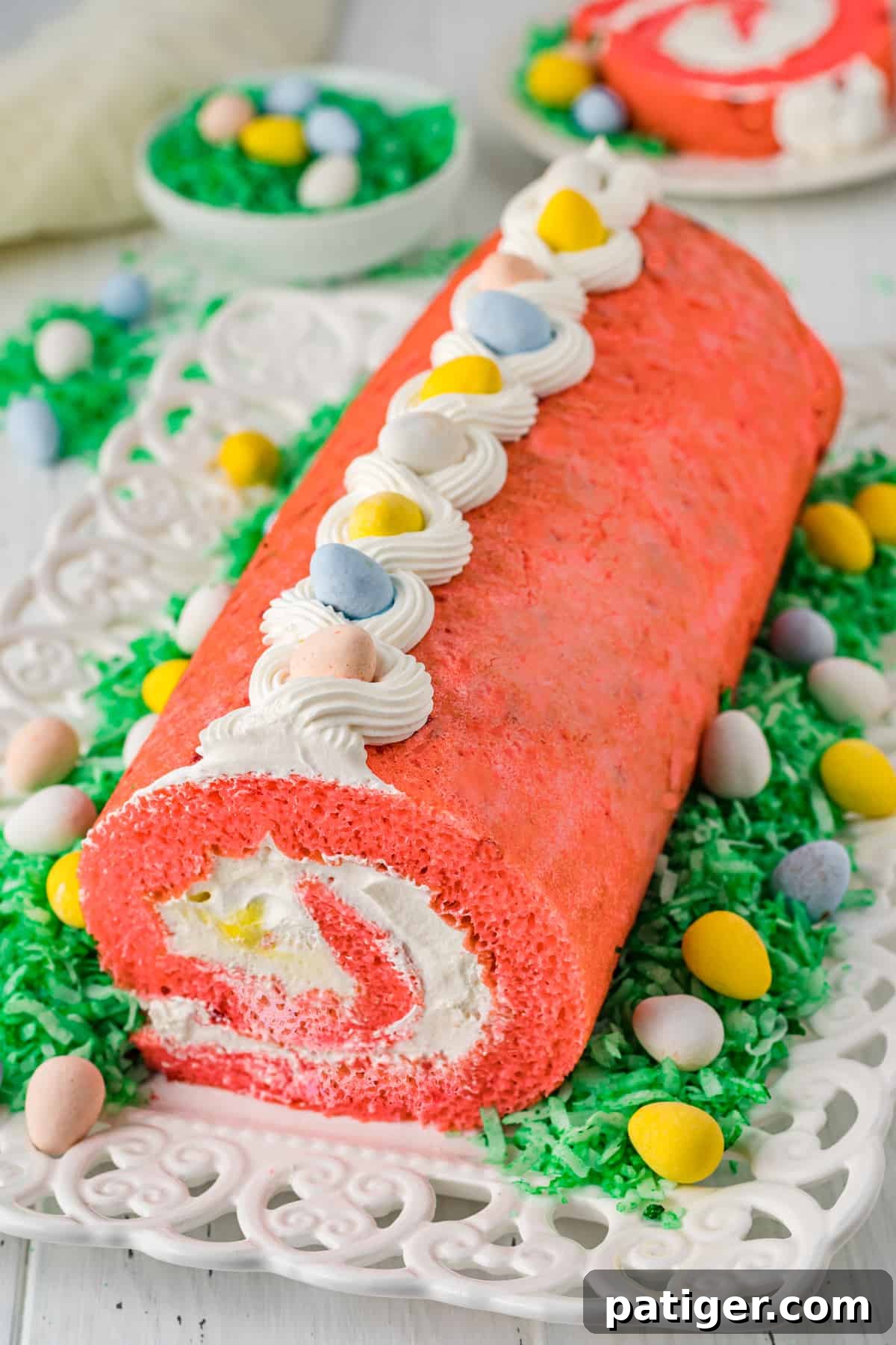 Vibrantly decorated Easter strawberry cake roll with fluffy whipped cream filling and colorful Cadbury mini eggs, ready for a festive celebration.