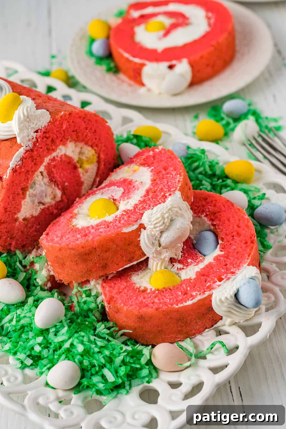 Close-up of a perfectly sliced Easter Cake Roll, revealing layers of strawberry cake, whipped cream, green shredded coconut 