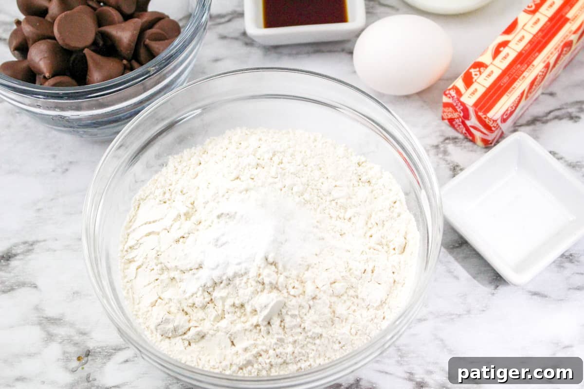 Spring Blossom Delights 4 A glass mixing bowl holds whisked dry ingredients for Easter Blossom Cookies: flour, baking soda, and salt, ready to be incorporated into the wet mixture.