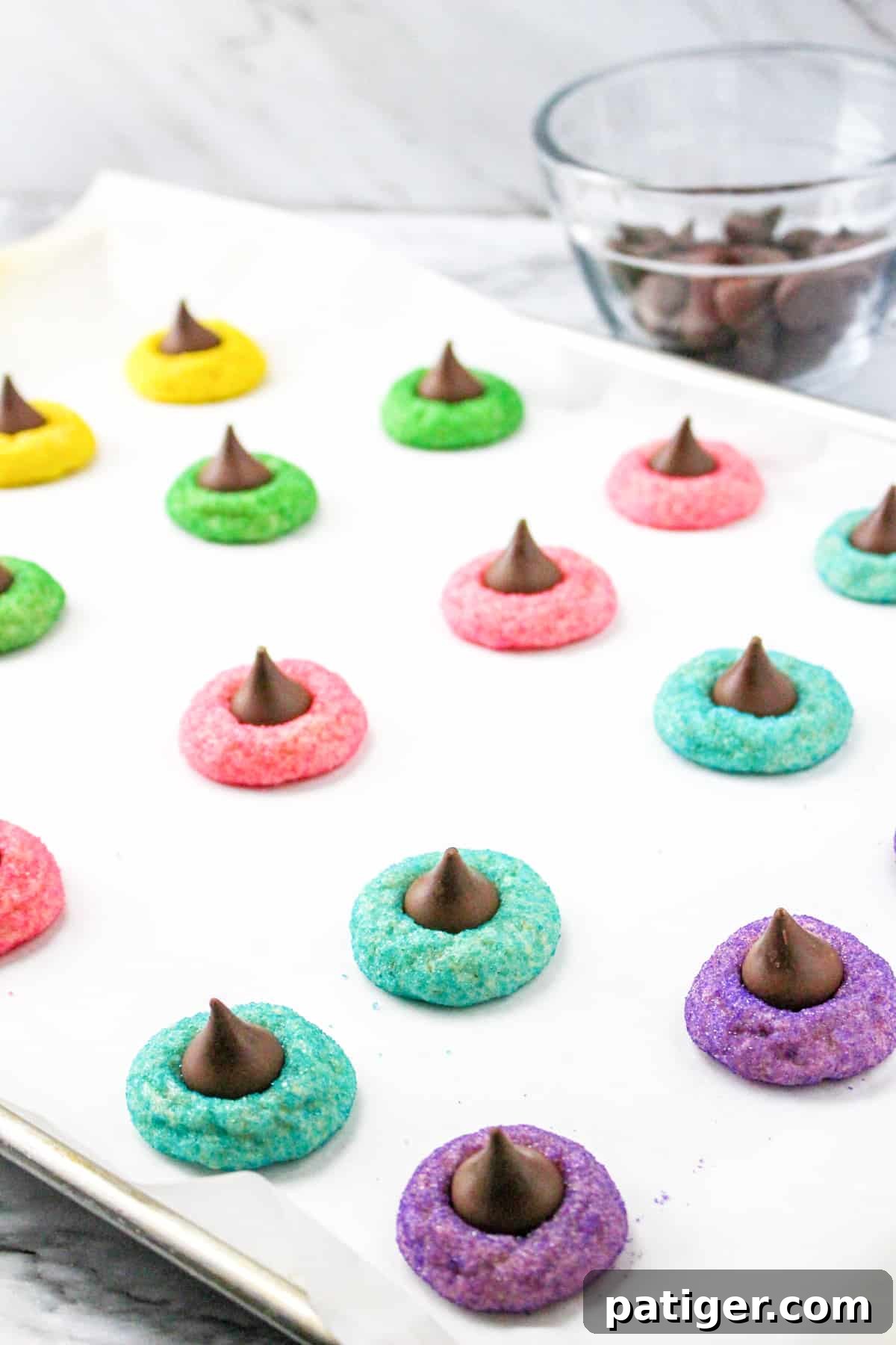 Spring Blossom Delights 9 A close-up view of freshly baked Easter Blossom Cookies with colorful sugar coatings and melted Hershey's Kisses, arranged on a parchment-lined baking sheet, ready to be enjoyed.