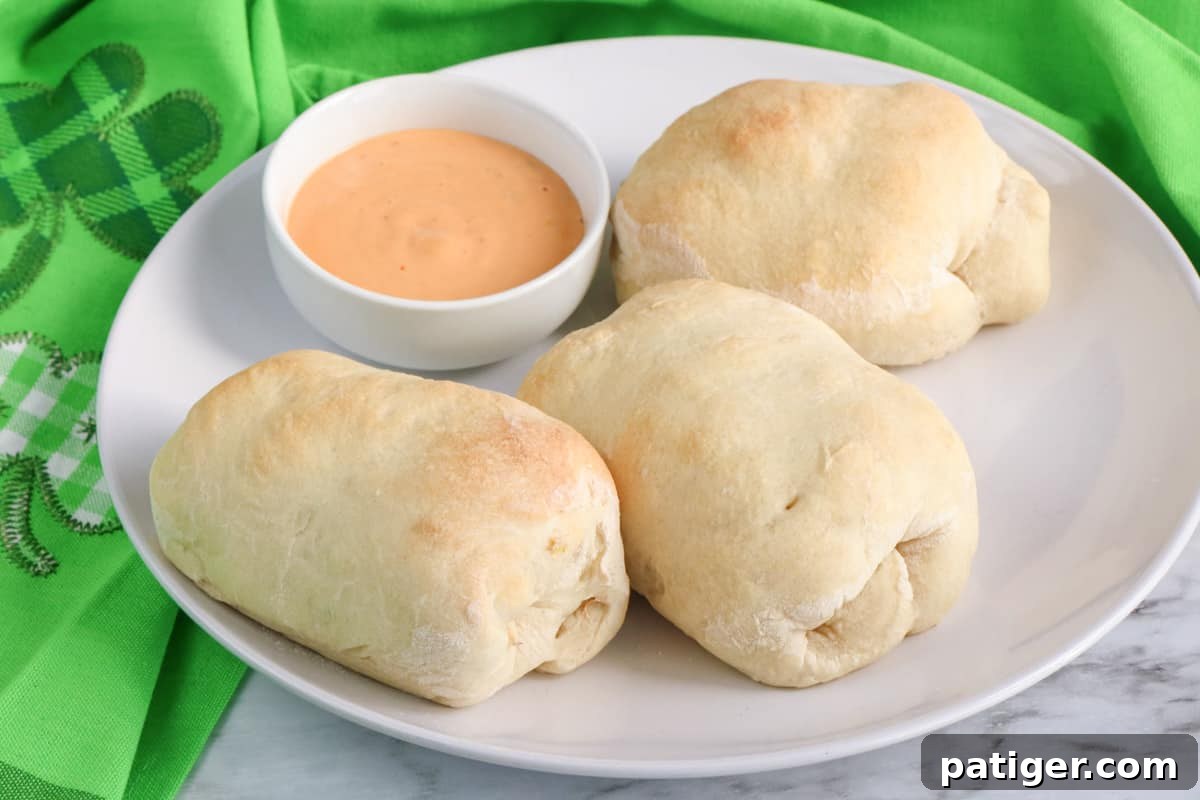 Reuben Pinwheels 2 Reuben rolls made with pizza dough on a white plate with a small bowl of thousand island dressing.