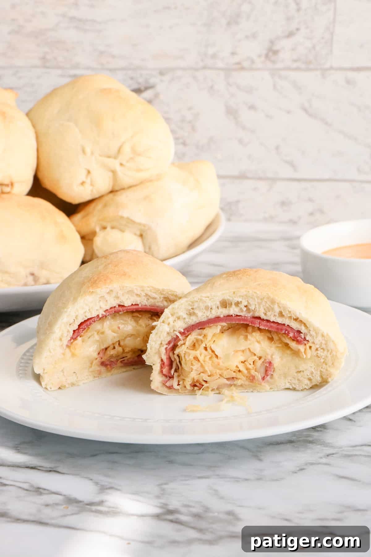 Reuben Pinwheels 3 Reuben Stromboli sliced in half to show corned beef, swiss, and sauerkraut inside. Additional Reuben Rolls are in the background.