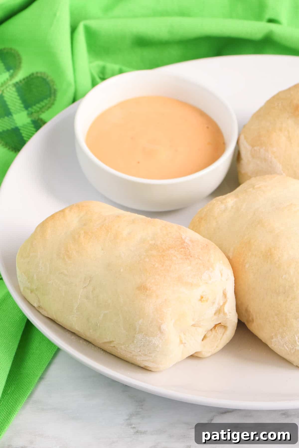 Reuben Pinwheels 9 Corned beef reuben roll up with pizza crust on white plate with bowl of thousand island dressing.