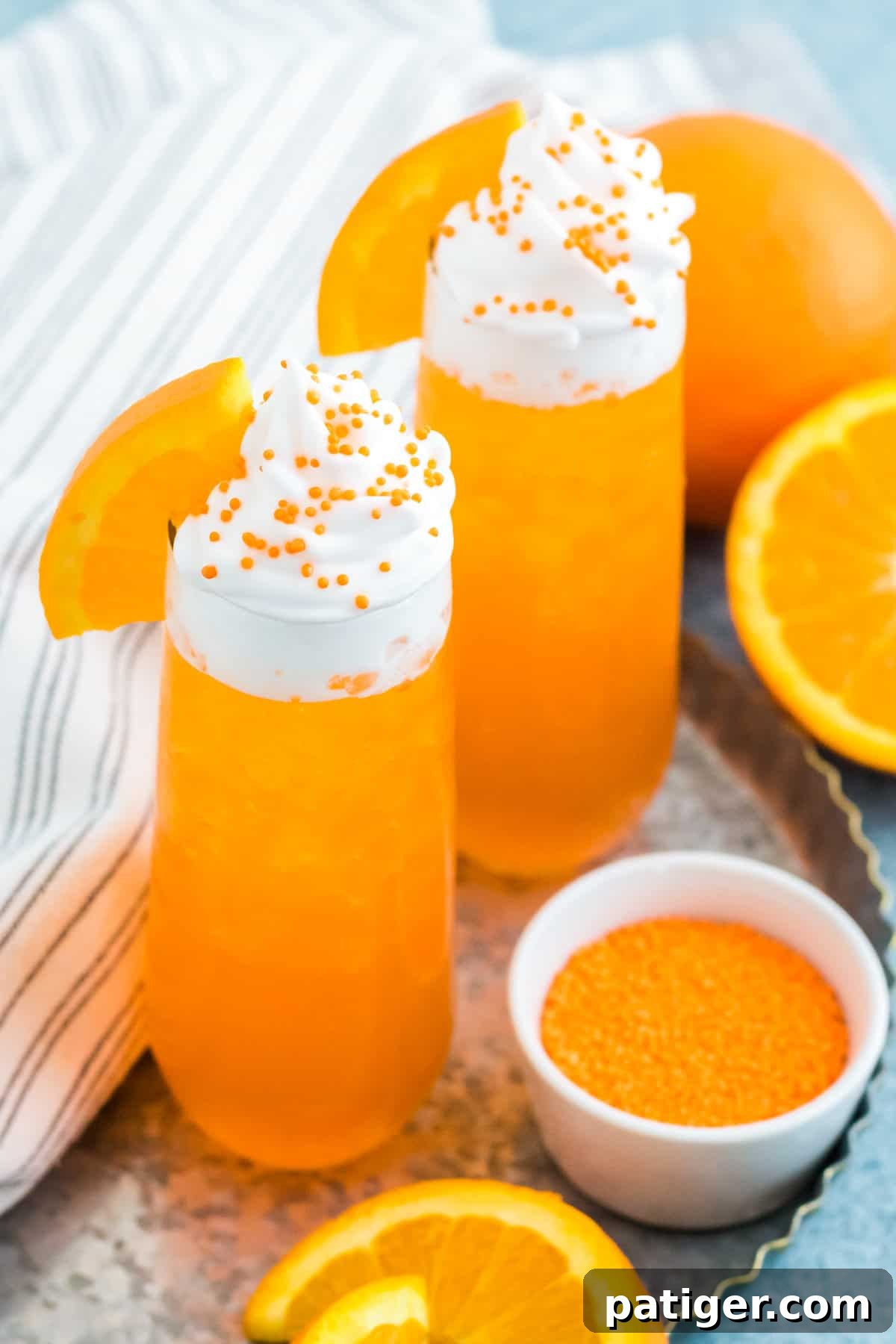 Two glasses of vibrant orange soda cocktail, generously topped with whipped cream, signifying a delicious and creamy beverage experience. The drinks are perfectly presented, ready to be enjoyed.