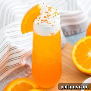 Orange creamsicle cocktail topped with whipped cream and fresh orange slice.