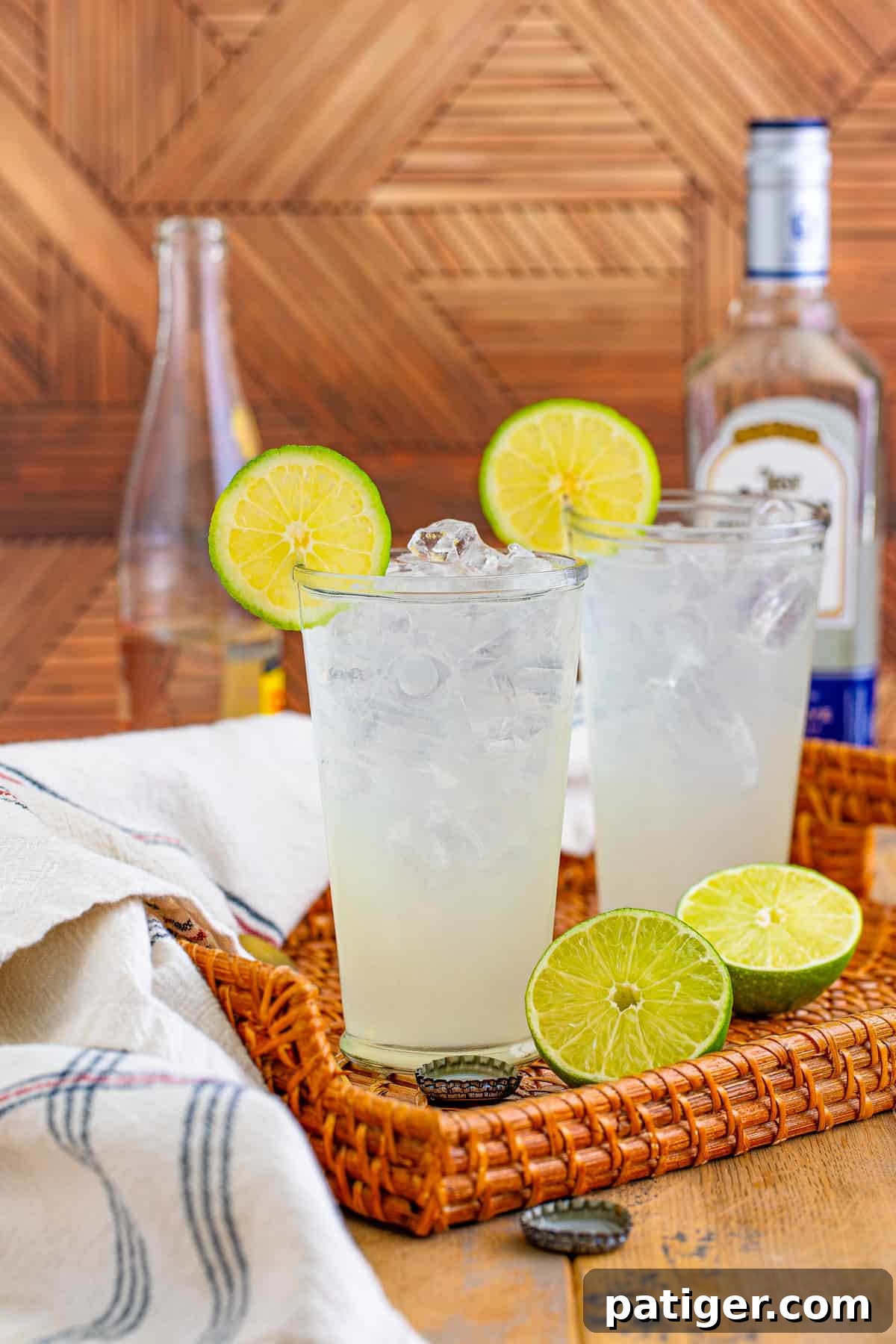 Two tall glasses of Texas Ranch Water cocktail garnished with lime wheels, sitting on a wooden surface.